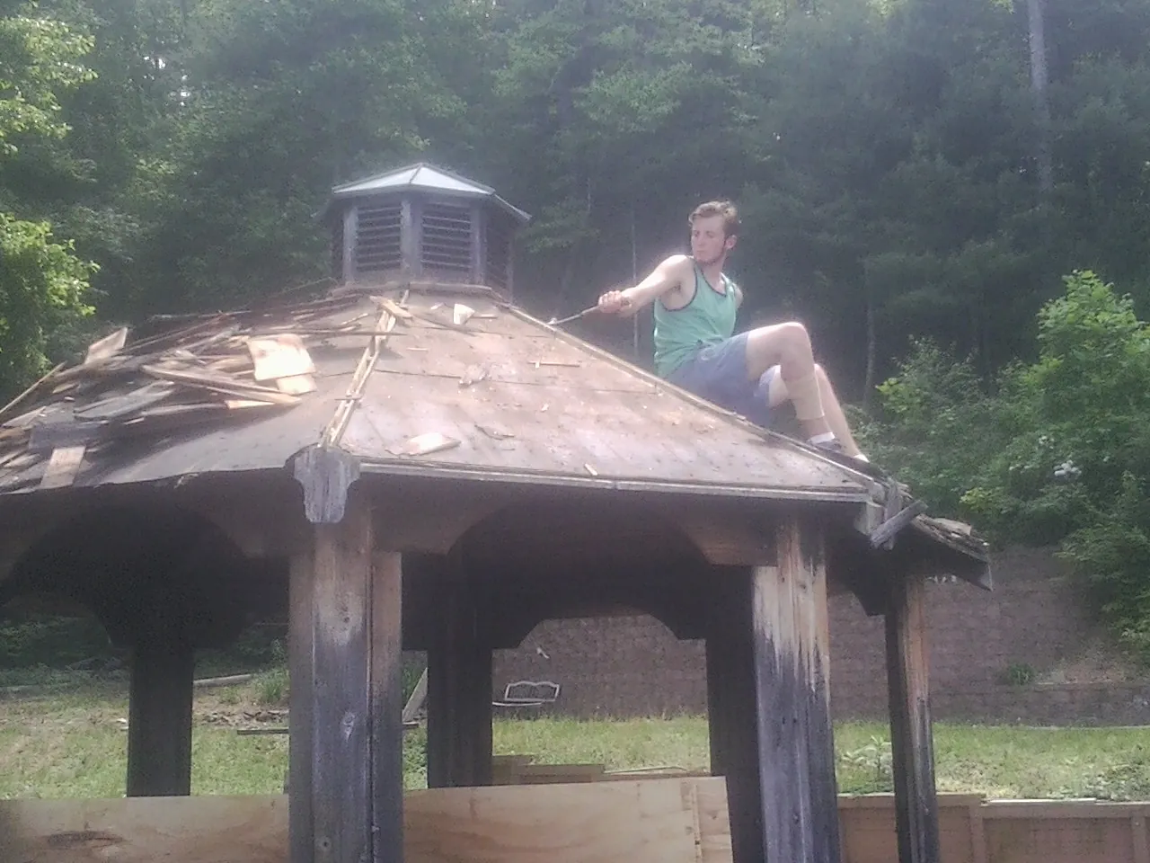 Tearing the old roof off a wooden gazebo before new shakes in Roundhill