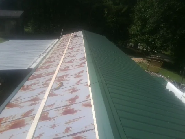 Old rusted panels beside newly installed green metal roofing — Wind Damage Roof Repair by Roofing Brothers in Roundhill