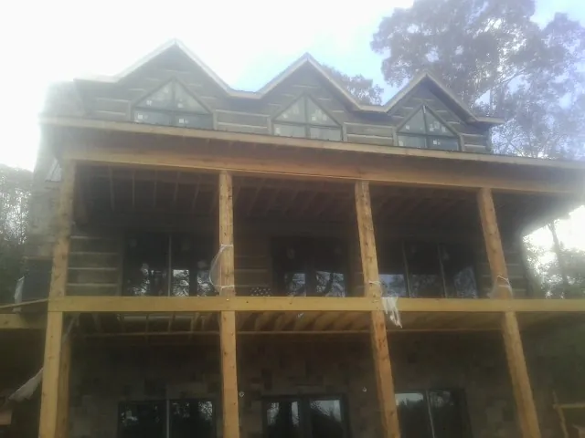 Dormers and porch framing on a large log home under construction — Roof Coating work by our crew in Roundhill