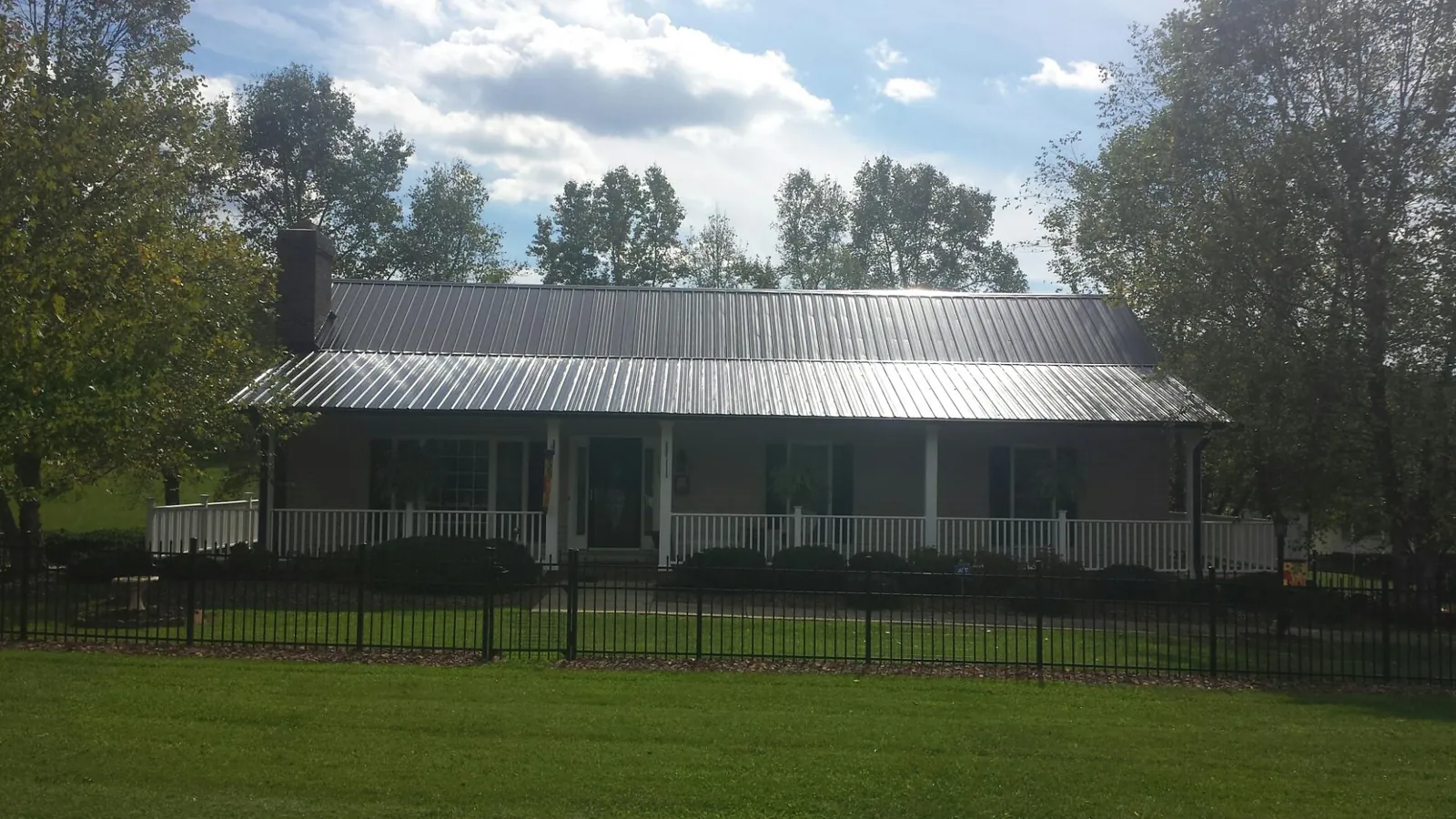 Gray metal roof on a brick ranch with a full width front porch — Gutter Guard Installation work by our crew in Roundhill