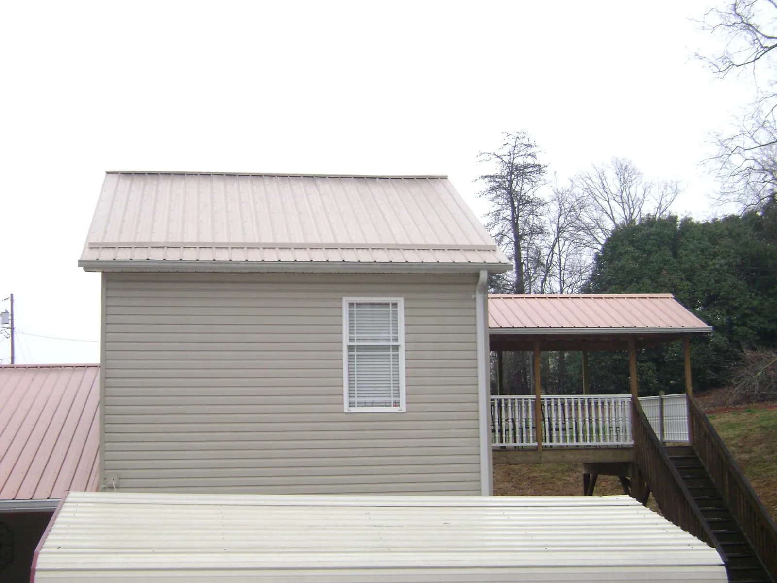 Tan metal roofs on a two story addition and attached porch, from a Roof Replacement job in Roundhill